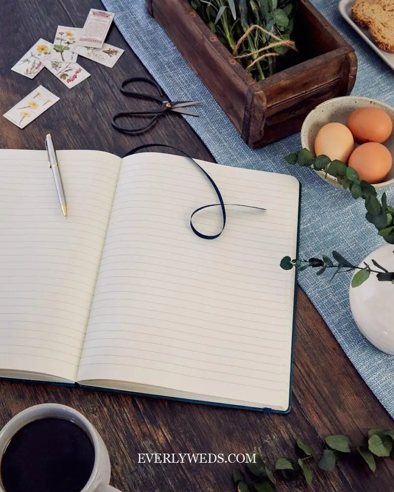 Creative wedding gift ideas including a personalized journal, potted plants, and homemade treats arranged on rustic wooden table
