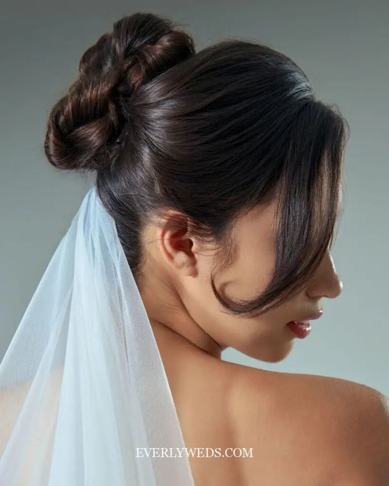 Elegant profile portrait of a bride showcasing an intricate updo with a white veil.
