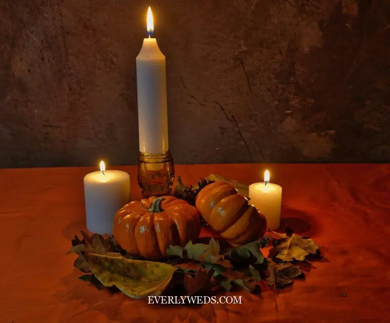 Pumpkins and lit candles on autumn leaves