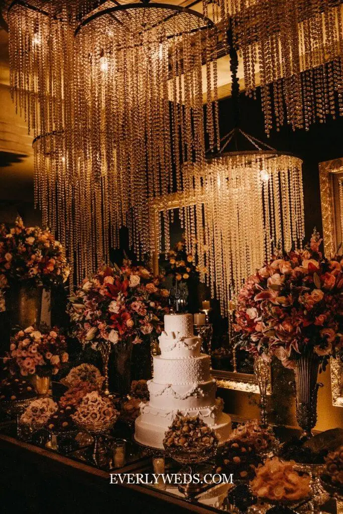 Elegant budget wedding cake display with crystal curtains, lush florals, and golden lighting for stunning reception decor