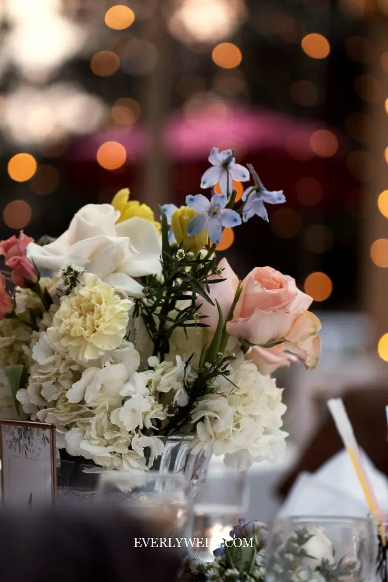 wedding set up reception table centerpieces using repurposed bridesmaid bouquets in mason jars and vintage vases