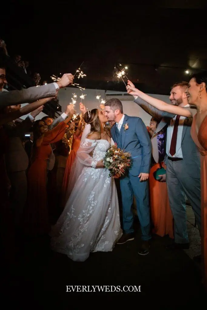 Bride and groom kiss under sparkler arch at romantic wedding celebration with unique save the date ideas