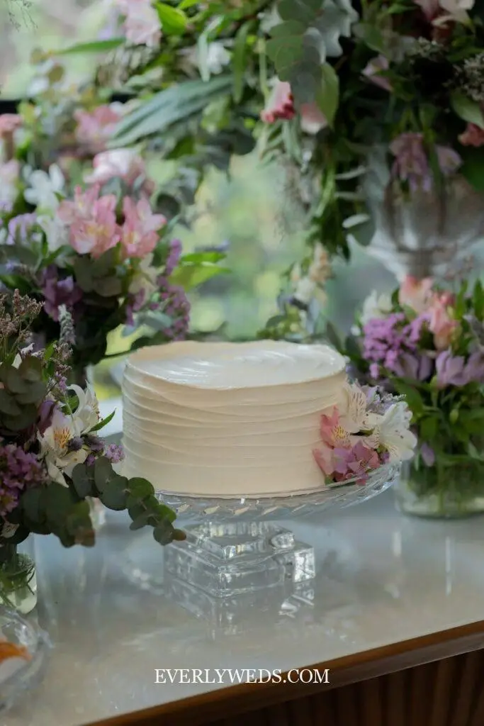 simple one tier wedding cake design with buttercream and floral topper for small intimate wedding