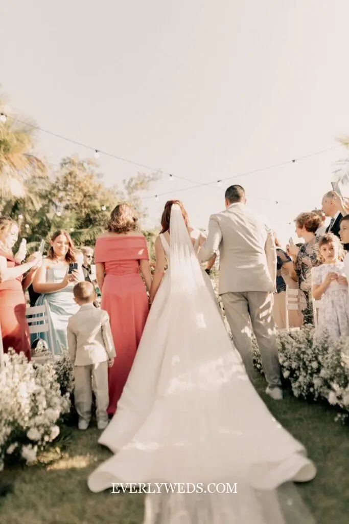 Bride and groom in first moments as married couple during wedding ceremony exit with guests cheering behind them