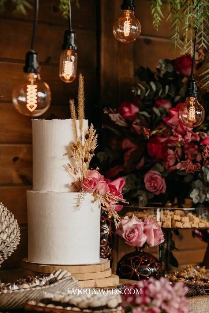 pressed dried floral wedding cake design with botanical flower accents on white buttercream best wedding cake design trend