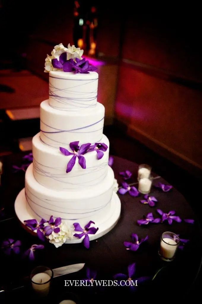 purple wedding cake design with lavender buttercream tiers and white floral accents for spring or fall wedding reception