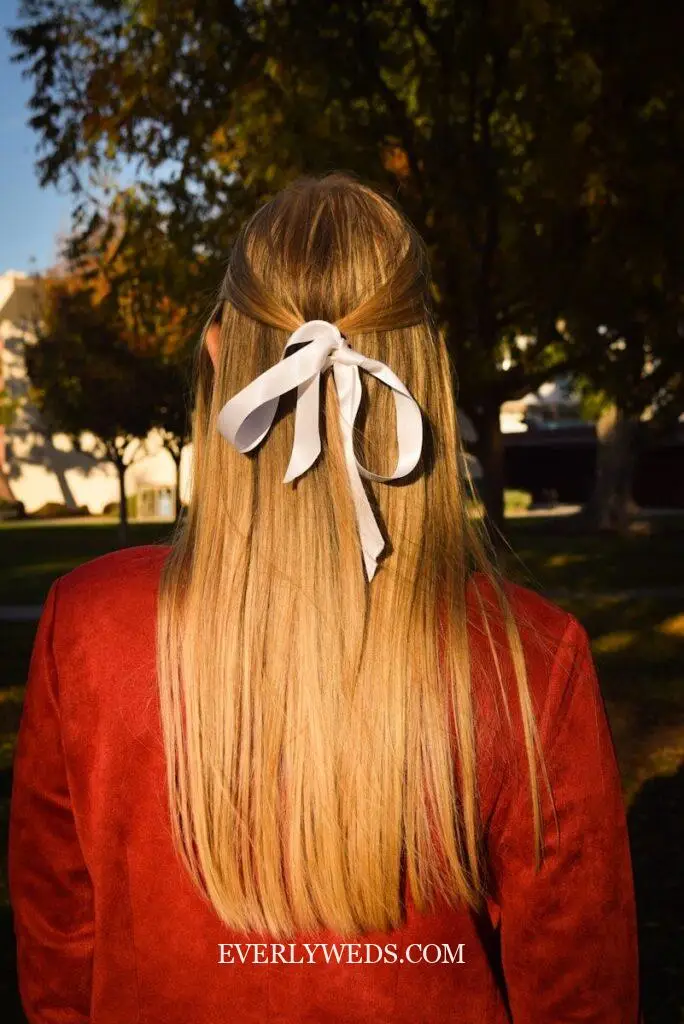 Woman's blonde hair with a white bow.
