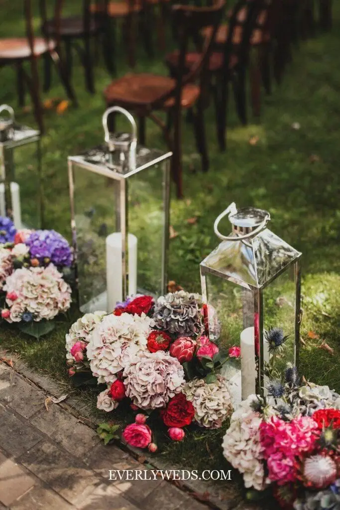 lanterns lining outdoor wedding walkway to ceremony with candles and greenery, wedding venue decorations outdoor simple