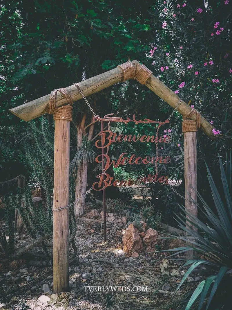 wedding entrance welcome sign on wood easel surrounded by fresh flowers and greenery elegant wedding entrance decor