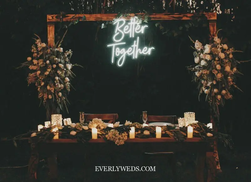 wedding set up reception indoor neon sign with surname over sweetheart table floral wall backdrop