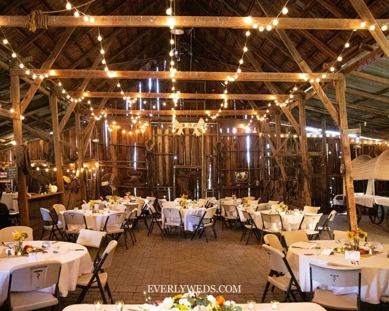 rustic barn event venue spaces interior with warm string lights and wooden beams wedding setup