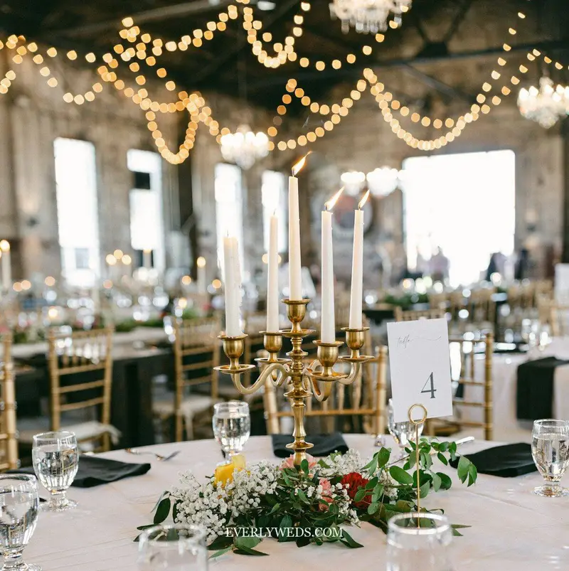 candles grouped on wedding reception tables with greenery and florals, romantic chic indoor wedding venue decorations simple