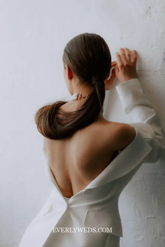 a woman in a white dress is holding her hair back