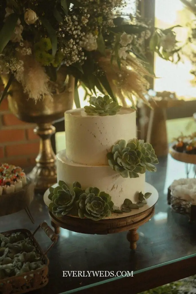 Simple wedding cake with greenery only, eucalyptus and fern wrapped around two tiers of white buttercream at an outdoor garden wedding