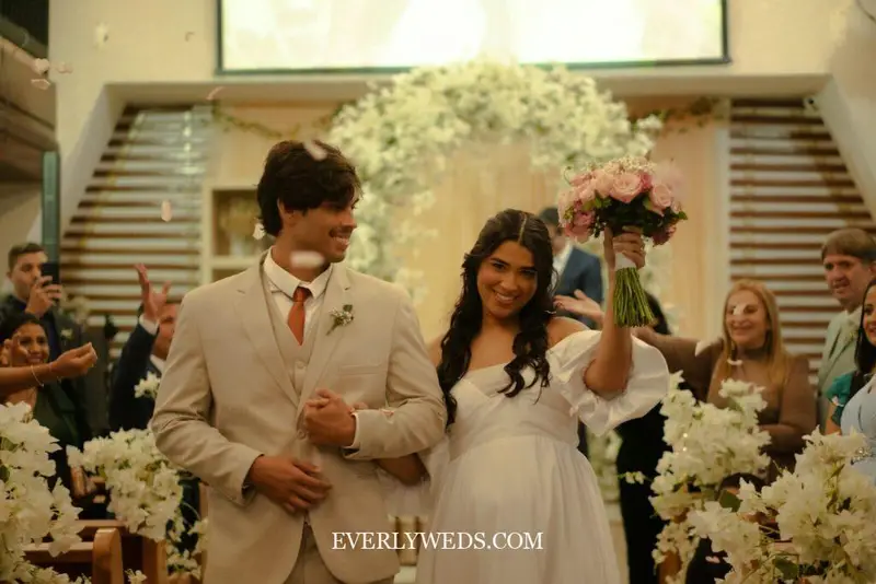 Wedding couple walking out smiling to fun recessional wedding songs while guests throw flower petals