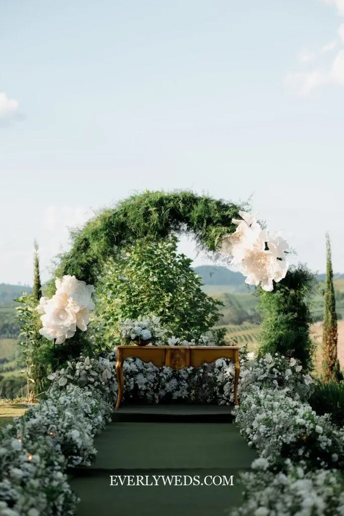 Green wedding ceremony backdrop with lush greenery arch decorated with white florals and eucalyptus for outdoor forest green wedding theme decor