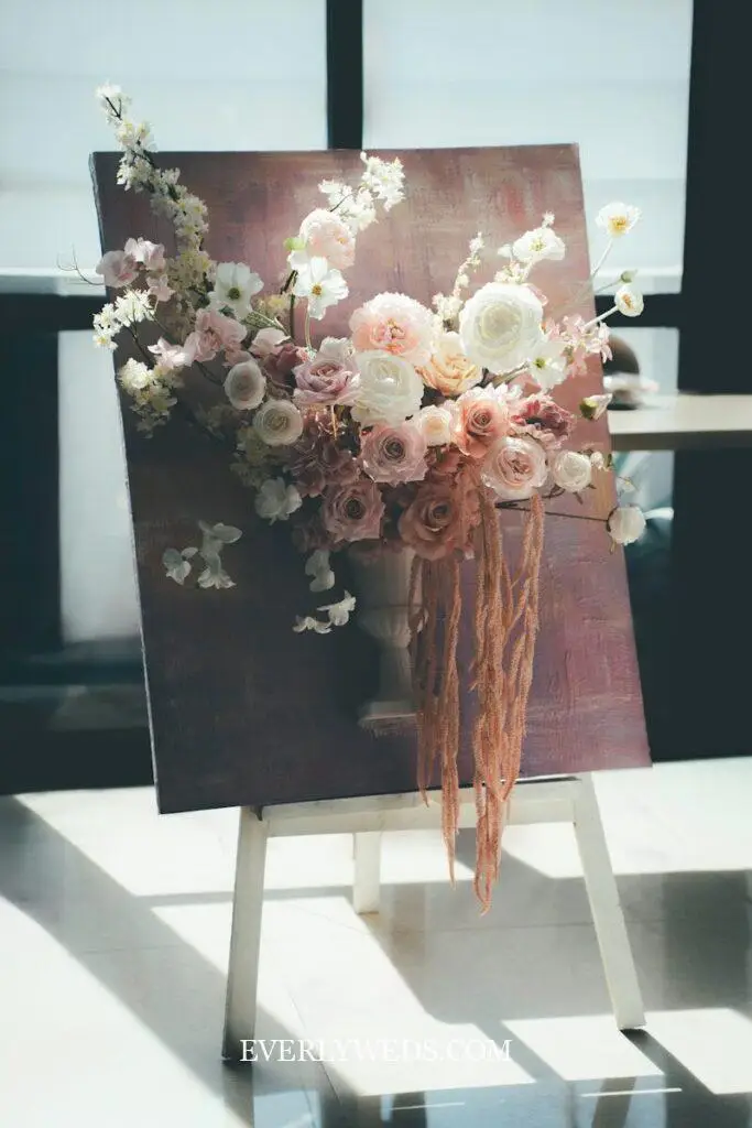 Creative wedding gift ideas featuring elegant floral arrangement with roses and ribbons on easel display