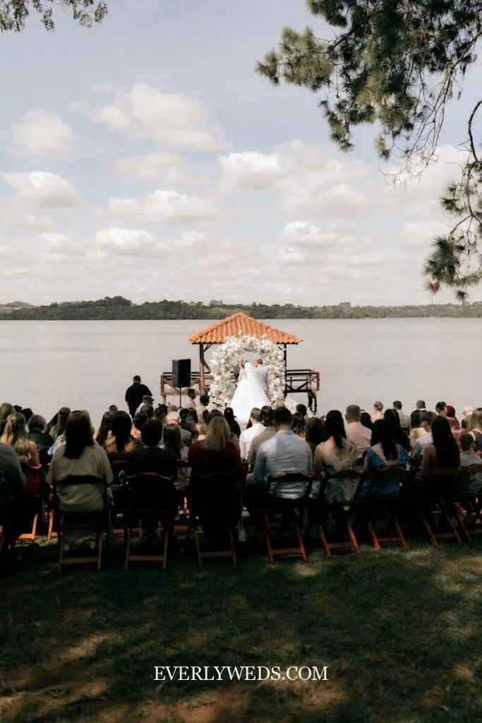Dream wedding venue outdoors lakeside reception at sunset with twinkle lights strung over dock and water reflection