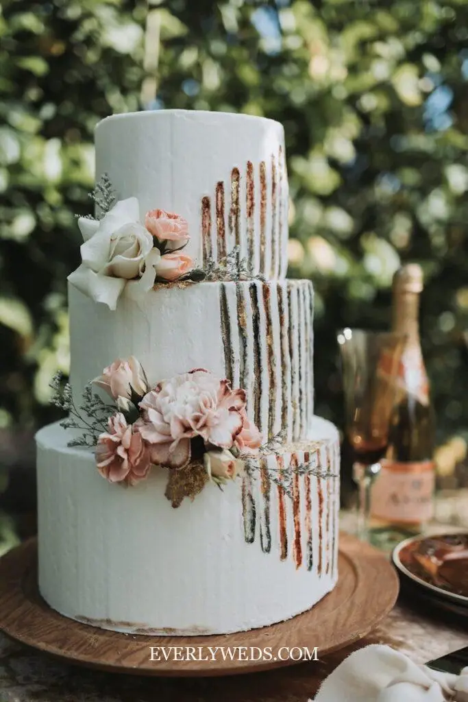 Here is a caption for the image: elegant three-tiered cake decorated with flowers.