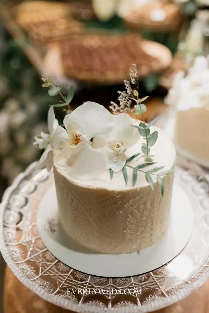 imple small wedding cake one tier on a marble stand at a cake table with flower arrangements, simple small wedding cake ideas for intimate celebrations